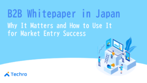 Blue hero banner for a B2B whitepaper in Japan; title text and an isometric data workspace with laptops, charts, and people, Techro logo bottom-left.