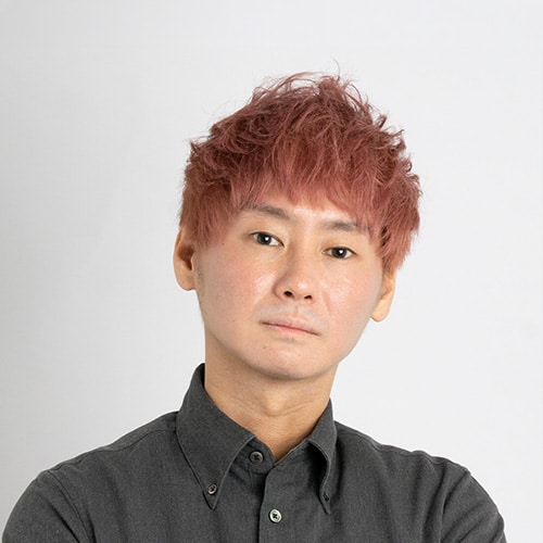 Portrait of a person with reddish-pink hair wearing a dark button-up shirt, looking at the camera with a neutral expression.